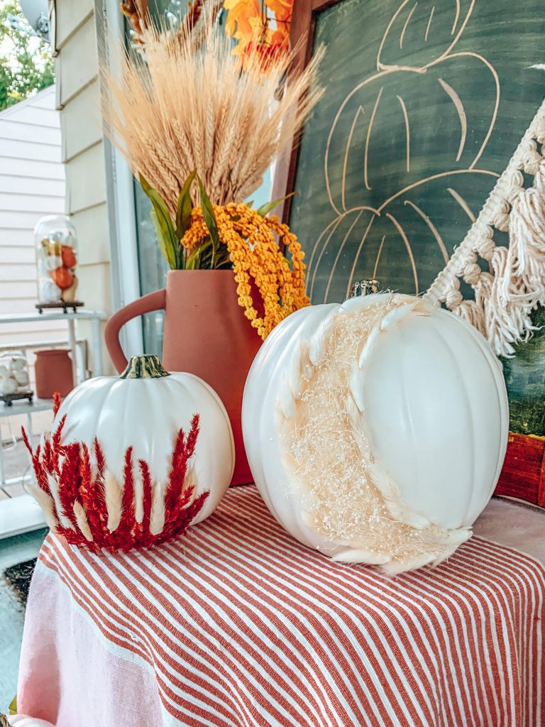 Fall pumpkins decorated with dried florals on front porch